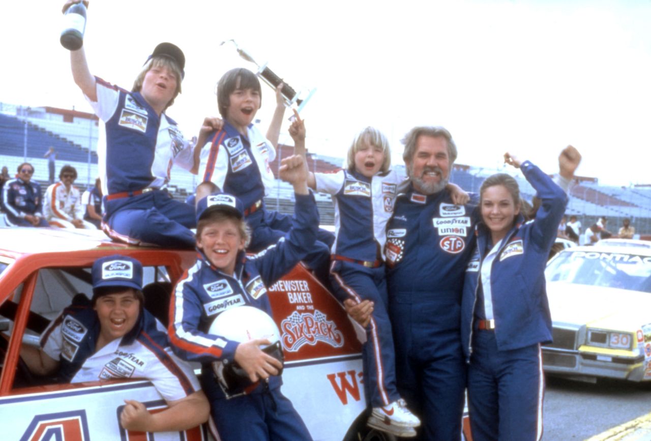 Rogers poses for a photo with members of the cast of the film "Six Pack" in 1982.