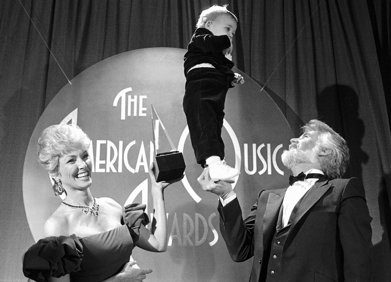 Rogers has his hands full as he balances his 13-month-old son Christopher backstage during the American Music Awards in 1983.