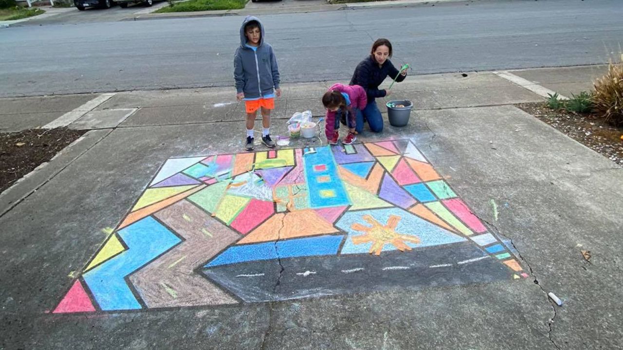 Daphne Sashin, her 8-year-old son Jack and 5-year-old daughter Lucy work on their sidewalk drawing as part of the community activity Sashin planned in their Mountain View, California, neighborhood.