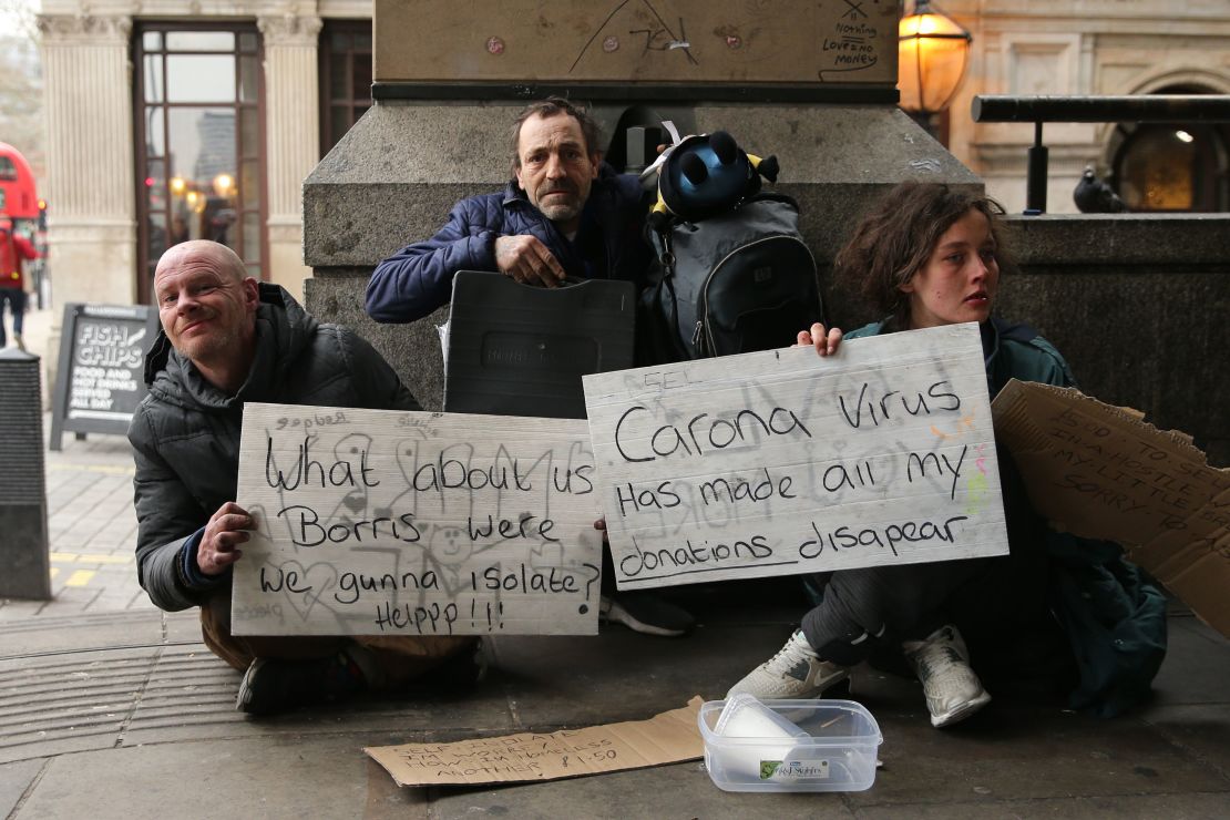 Homeless people hold signs appealing for help as they pose for a photograph in London on March 19.