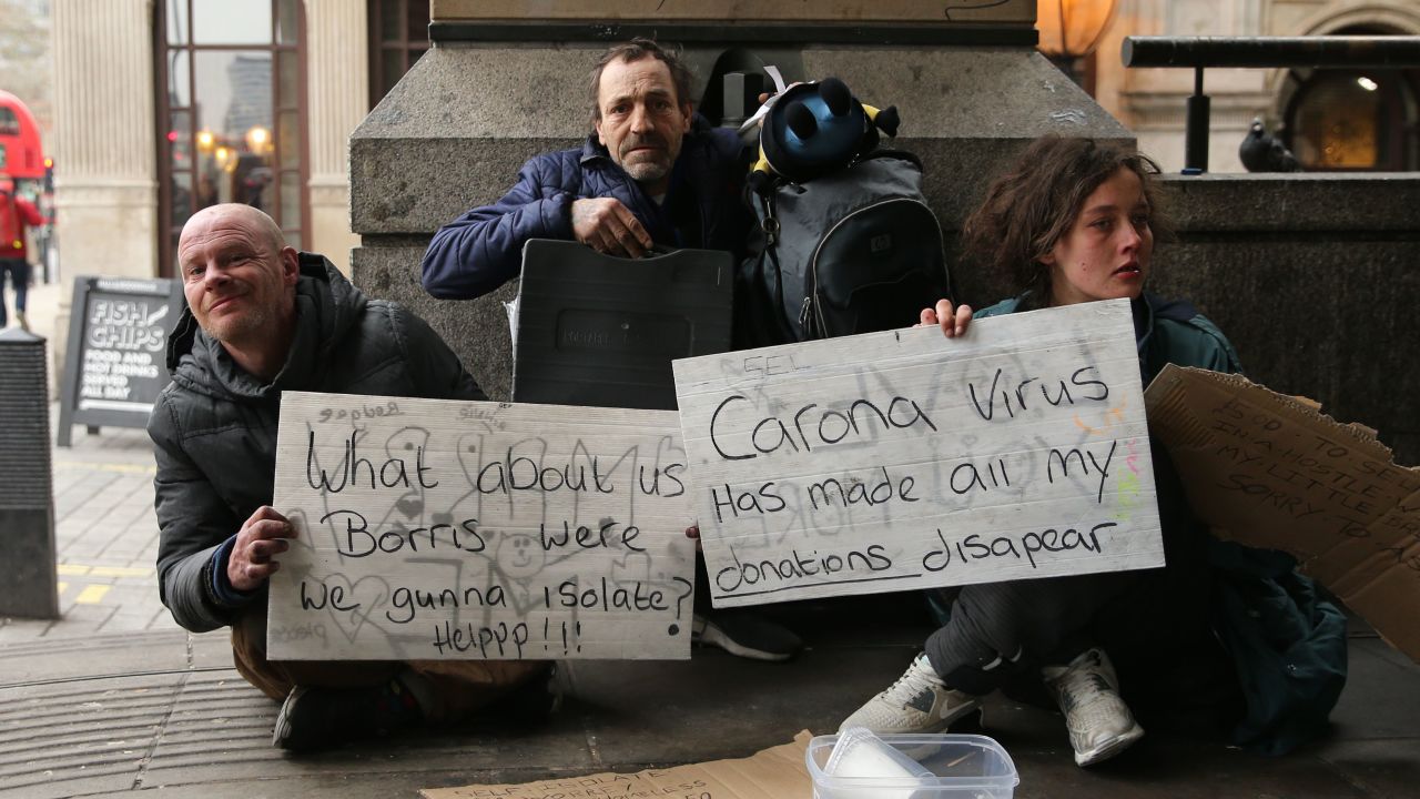 Homeless people hold signs appealing for help as they pose for a photograph in London on March 19.