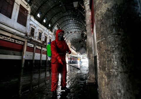 A Syrian Red Crescent member sprays disinfectant along an alley of the historic Hamidiyah market in Damascus, Syria.