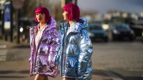 PARIS, FRANCE - MARCH 03: Fashion twins Ami and Aya "AmiAya" are seen ; a guest wears a pink polo shirt, a purple shiny puffer coat,  a guest wears a blue shiny glittering puffer coat, outside Lacoste, during Paris Fashion Week - Womenswear Fall/Winter 2020/2021 on March 03, 2020 in Paris, France. (Photo by Edward Berthelot/Getty Images)
