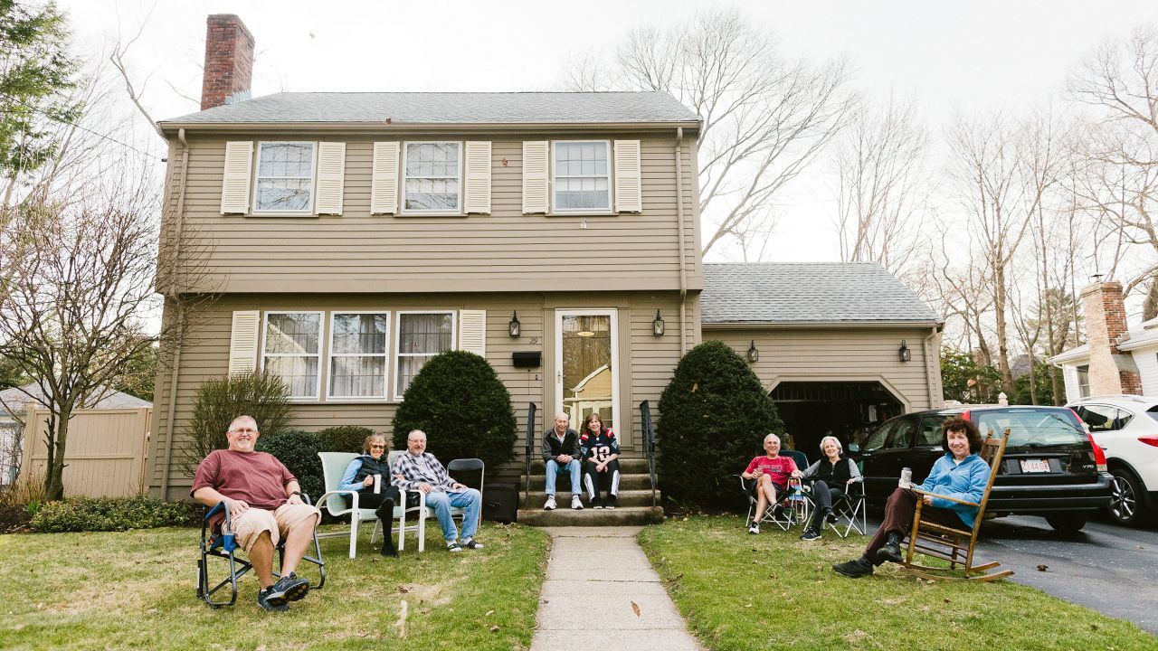 A group of people photographed on one of their front lawns. The group, who was enjoying a warm Friday afternoon, maintained six feet of distance between each other. 