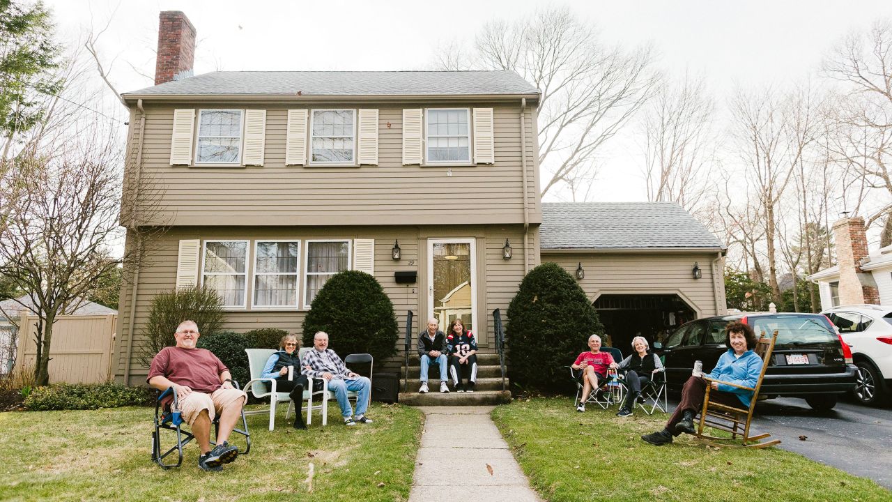 A group of people photographed on one of their front lawns. The group, who was enjoying a warm Friday afternoon, maintained six feet of distance between each other.