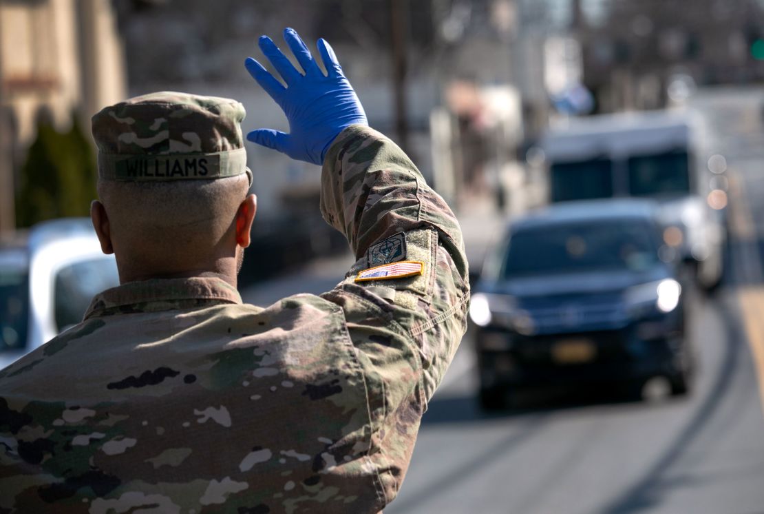 A National Guard soldier stops traffic as fellow troops distribute food in New Rochelle, New York.