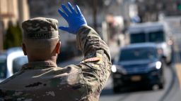 A U.S. National Guard soldier stops traffic as fellow troops distribute food to local residents at the WestCop community center on March 18, 2020 in New Rochelle, New York. The troops have been deployed to New Rochelle, which has been a hot spot for the COVID-19 pandemic in the U.S.