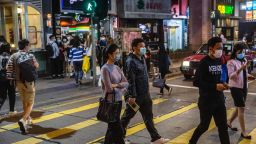 Pedestrians wearing facemasks amid concerns over the spread of the COVID-19 novel coronavirus, walk through a road in the central district of Hong Kong on March 21, 2020. (Photo by ISAAC LAWRENCE / AFP) (Photo by ISAAC LAWRENCE/AFP via Getty Images)