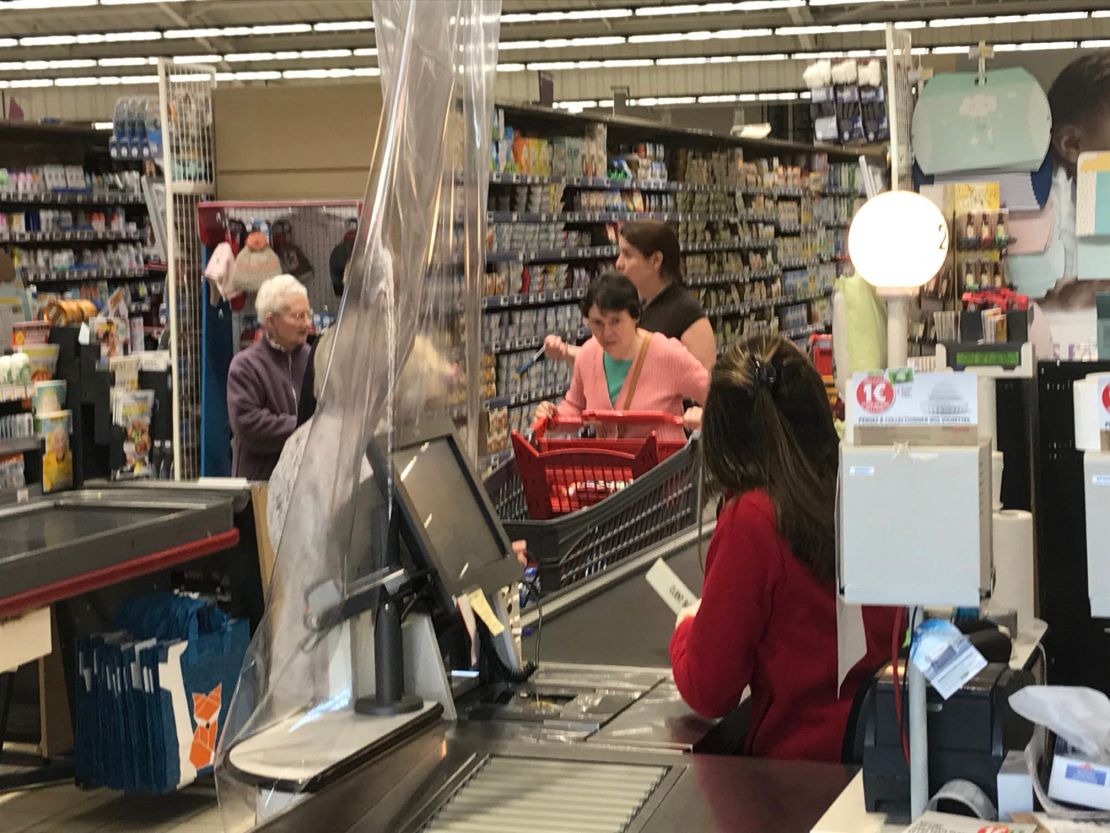 Cashiers separated from customers by plastic.