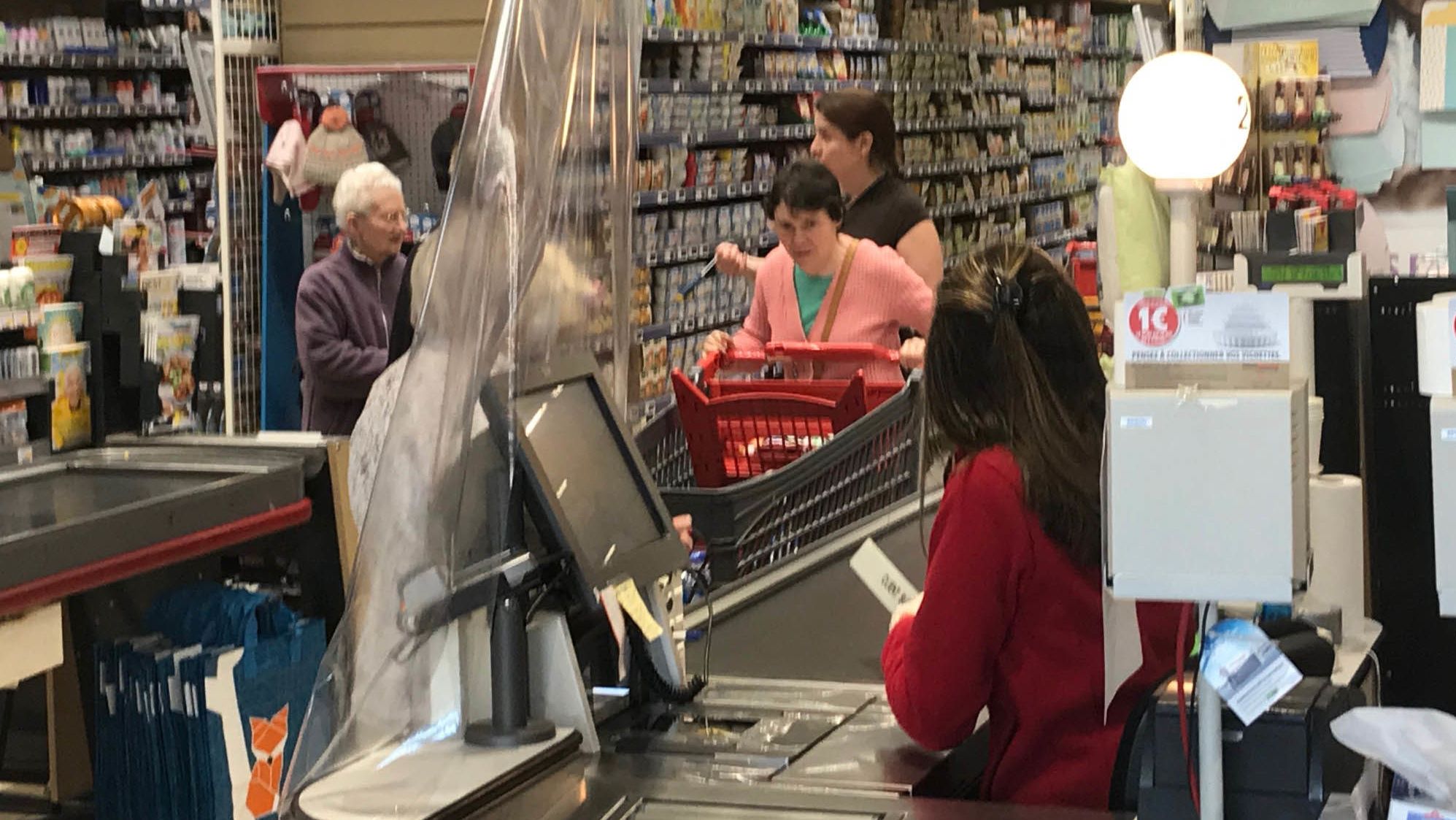 Cashiers separated from customers by plastic.