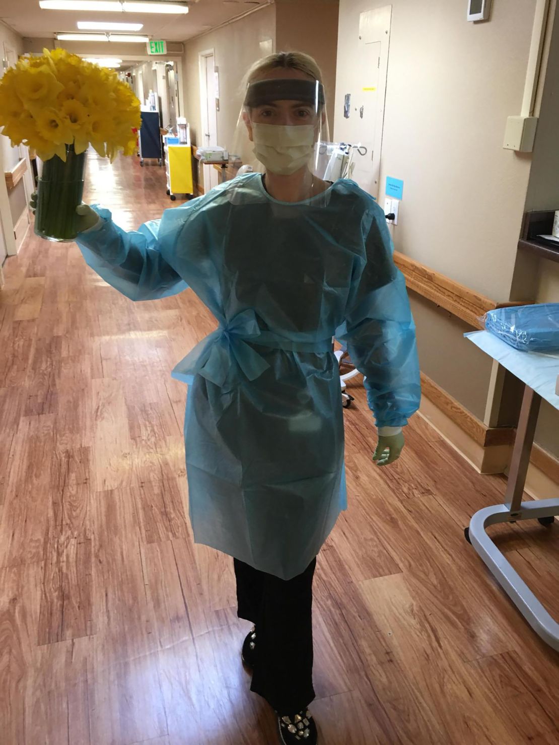 Izabela Ivanov, in her full protective gear, holds daffodils amid the outbreak.