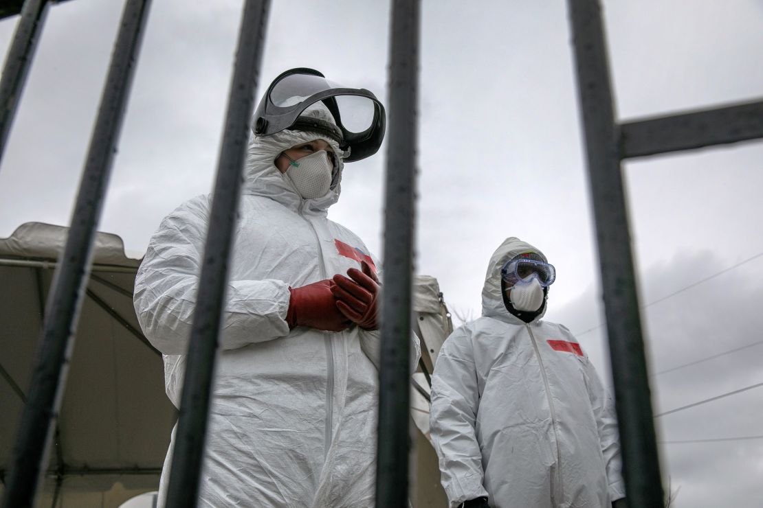 Health workers dressed in personal protective equipment await new patients at a drive-thru coronavirus testing station in Stamford, Connecticut, on March 23, 2020.