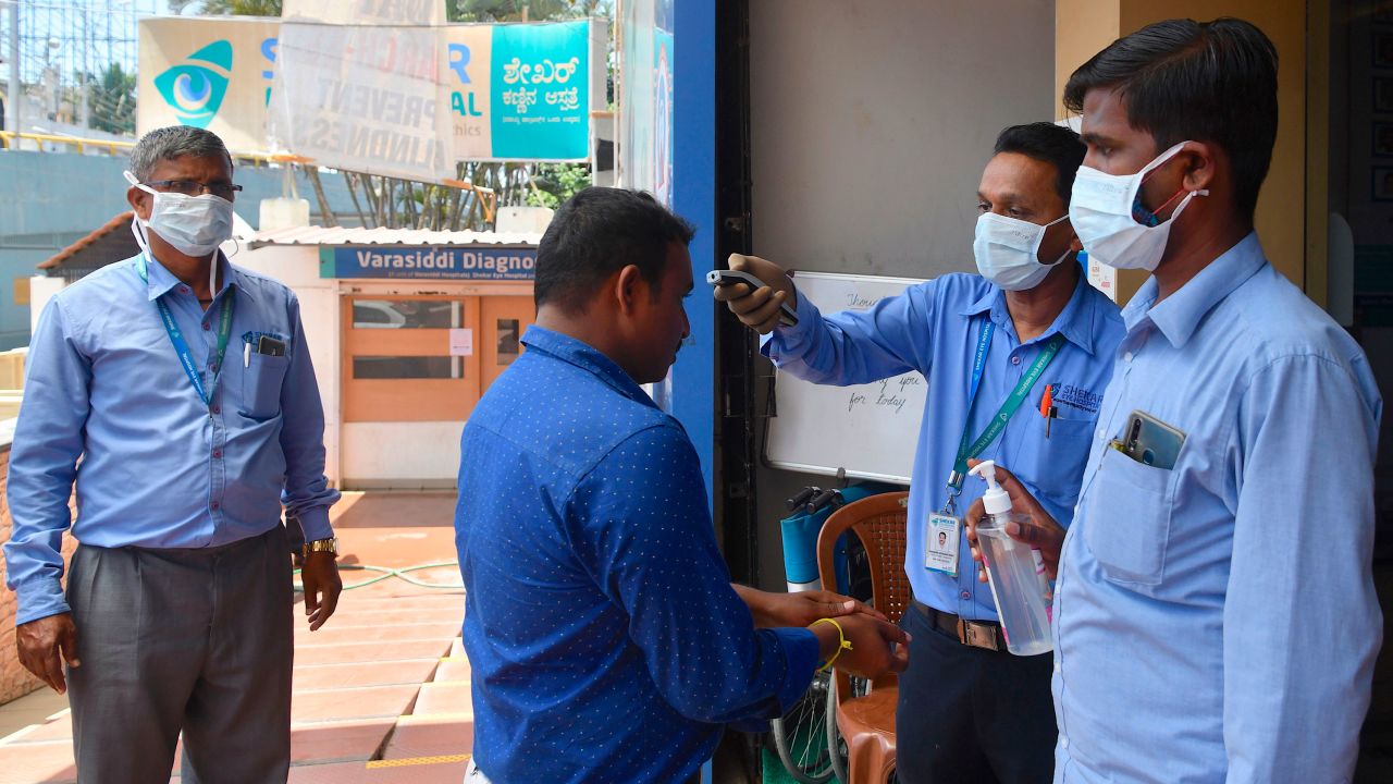 Security personnel wear face masks as they check the temperature of visitors to a hospital in Bangalore on March 16, 2020.