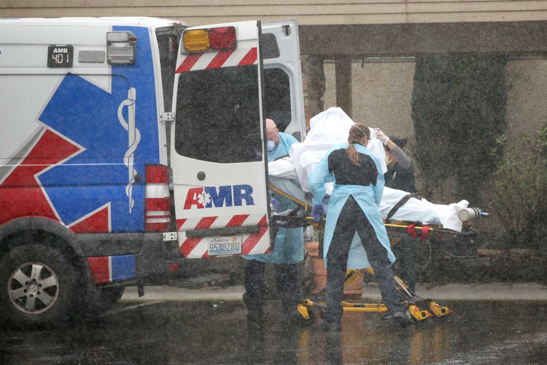 A patient is shielded while being put into an ambulance outside the Life Care Center of Kirkland on March 7, 2020. 