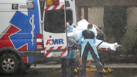 A patient is shielded while being put into an ambulance outside the Life Care Center of Kirkland on March 7, 2020. 