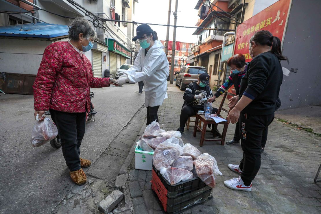 People buy pork at the gate of a closed residential community in Wuhan on March 18.
