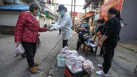 People buy pork at the gate of a closed residential community in Wuhan on March 18.