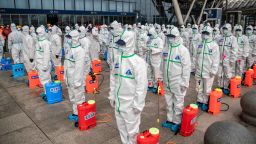 Staff members line up at attention as they prepare to spray disinfectant at Wuhan Railway Station in Wuhan in China's central Hubei province on March 24, 2020. - China announced on March 24 that a lockdown would be lifted on more than 50 million people in central Hubei province where the COVID-19 coronavirus first emerged late last year. (Photo by STR / AFP) / China OUT (Photo by STR/AFP via Getty Images)