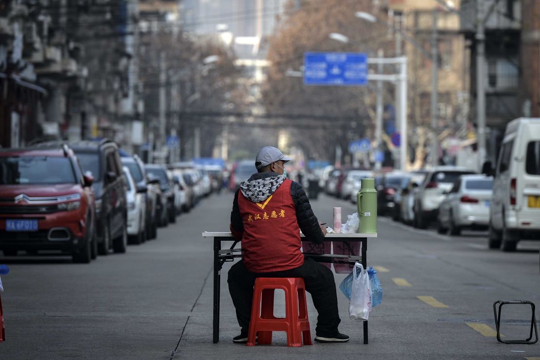 A volunteer guards a temporary wall blocking a road in Wuhan on March 12.