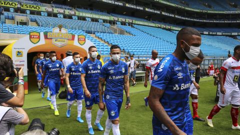 Players of Gremio enter the field wearing masks before the match against Sao Luiz.