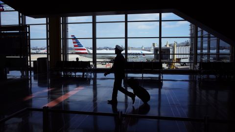 A flight crew member walks in a terminal of Ronald Reagan Washington National Airport in Arlington, Virginia, on March 17, 2020.