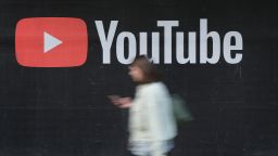 A young woman with a smartphone walks past a billboard advertisement for YouTube on September 27, 2019 in Berlin, Germany. 