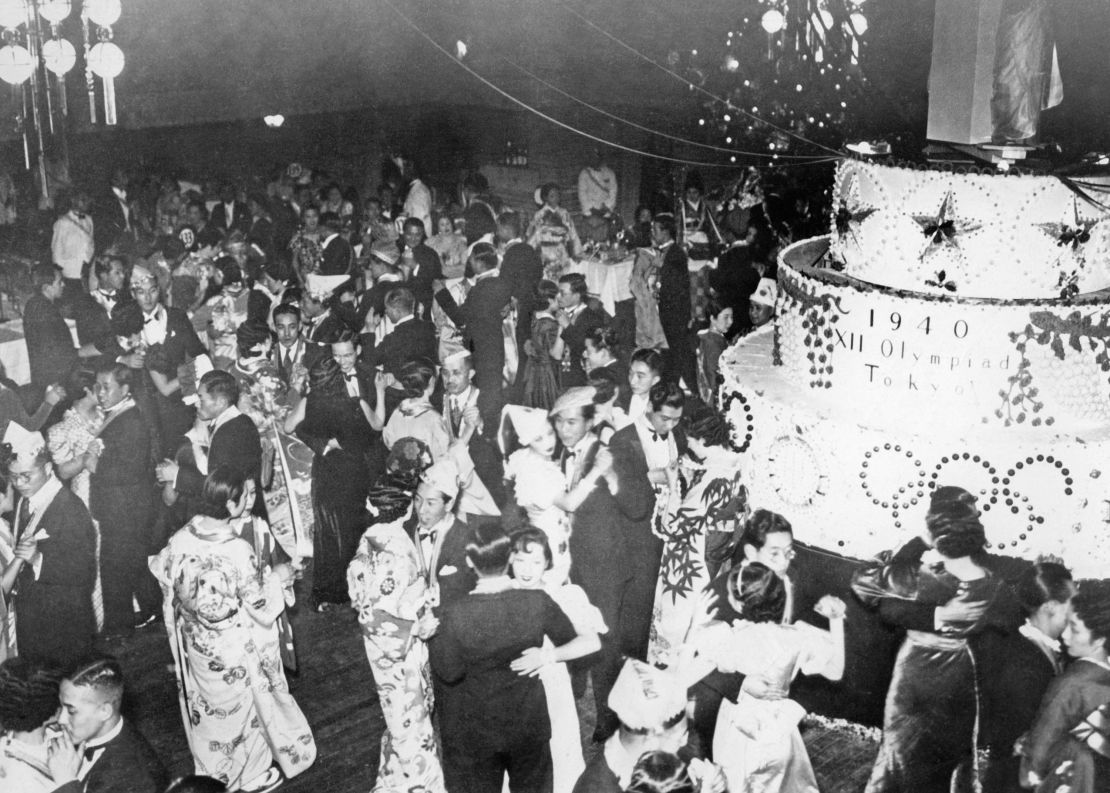 At a Christmas party in Tokyo, on the right is a large cake with the inscription 1940 XII Olympiad Tokyo to celebrate the upcoming Olympics in Japan.