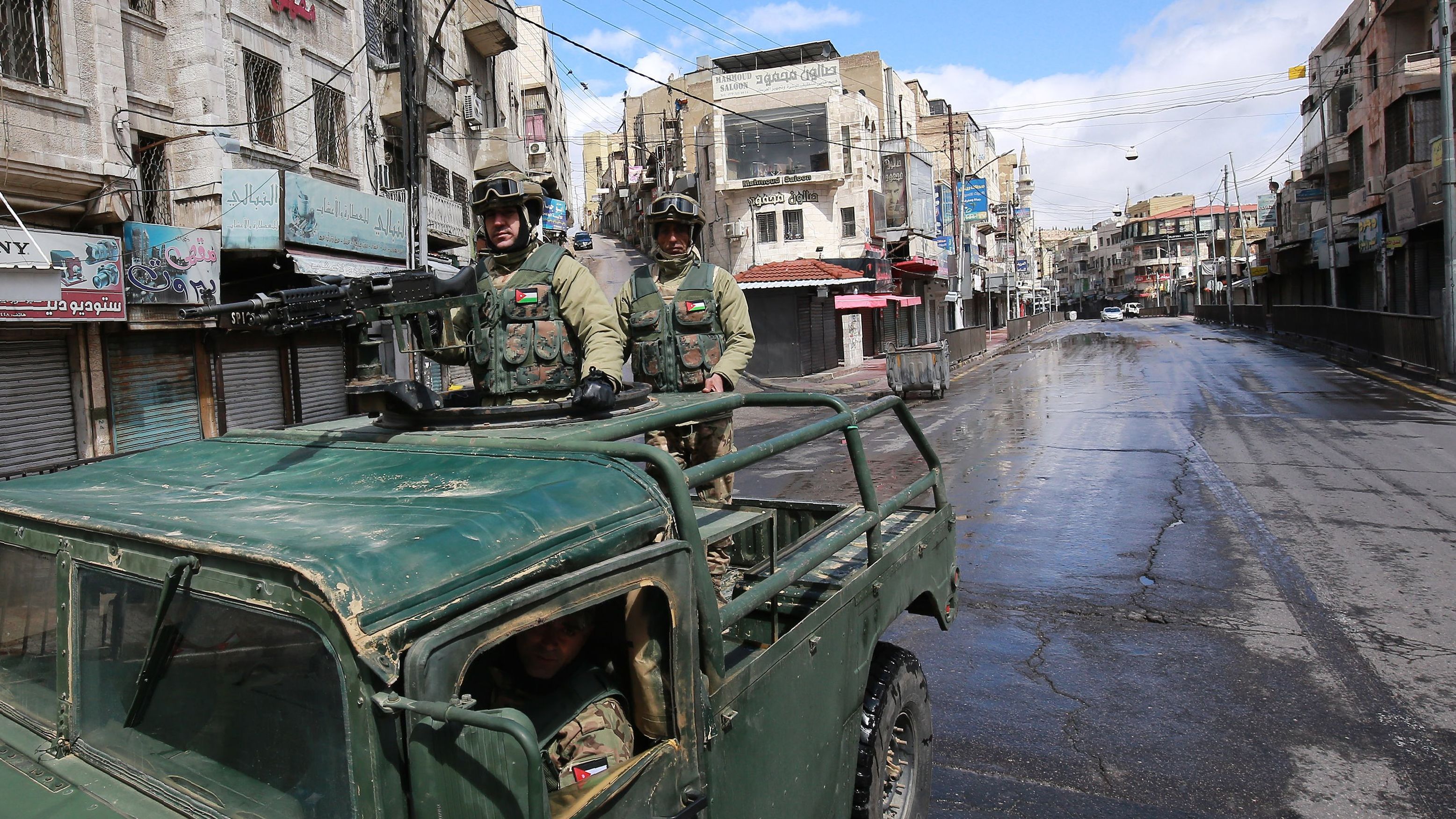 Soldiers patrol atop a military vehicle on deserted street in Amman.