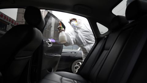 A worker wears protective clothing as he disinfects a car for Chinese ride hailing company Didi in Beijing in February.