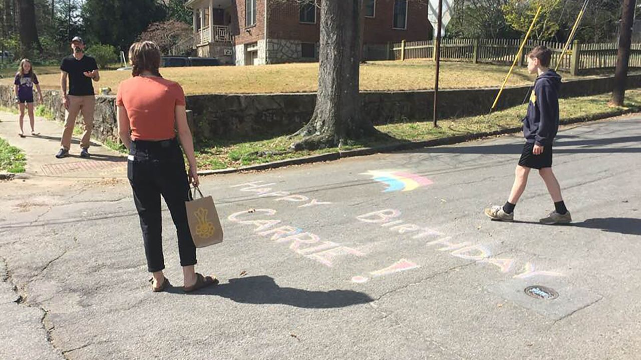 Friends draw in chalk on the street to wish Carrie Crespino a happy birthday.