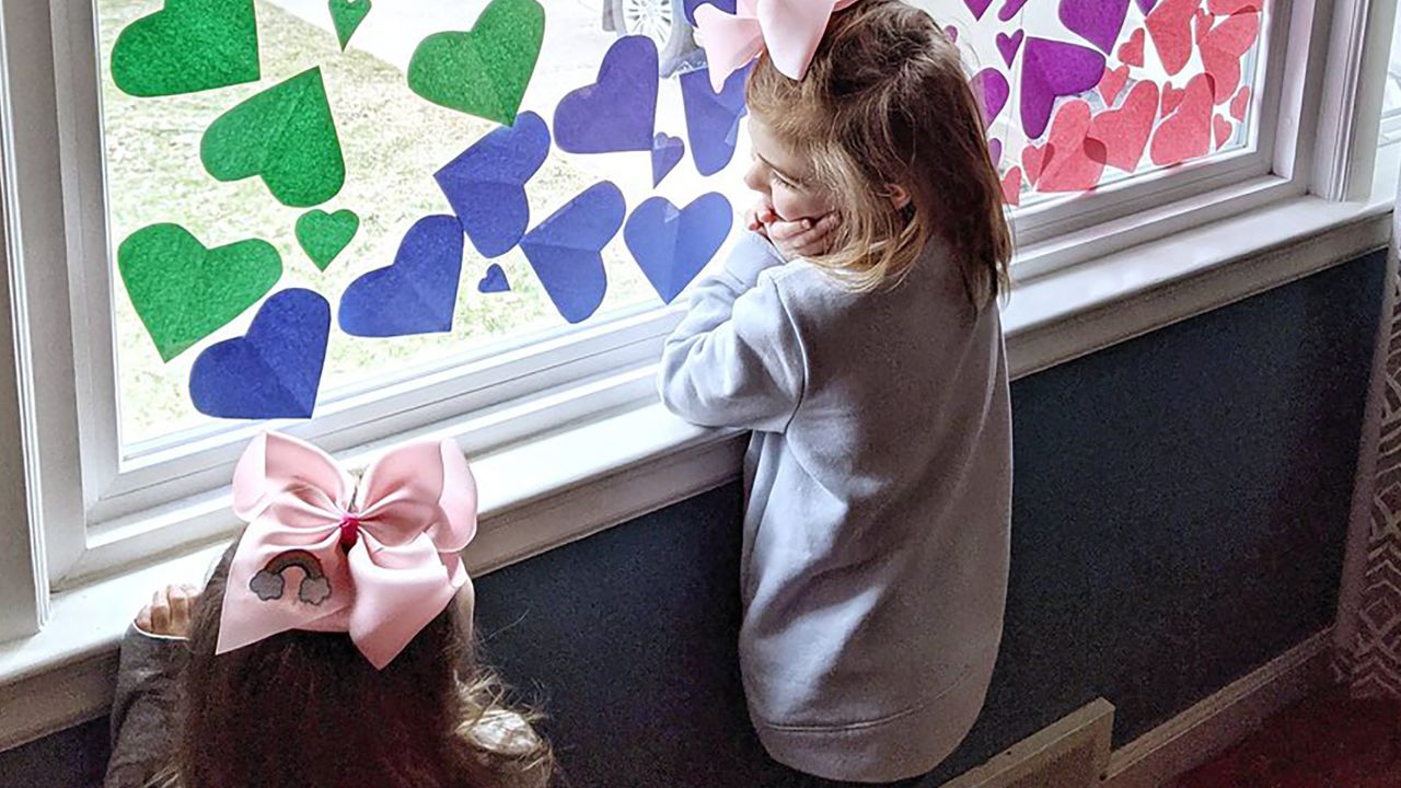 Josephine, 5, and Nora, 2, look out their rainbow heart-filled window in Michigan. Their mother, Jenna Webb, said she wanted to "bring love and joy to essential workers" in their neighborhood.