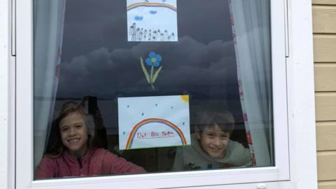 Eight-year-olds Olivia and Kristoffer stand next to their rainbow drawings in Norway.