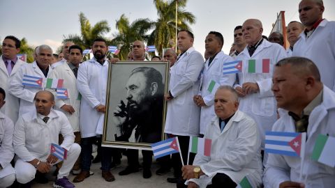 Doctors and nurses of Cuba's Henry Reeve International Medical Brigade pose with a portrait of Cuban late leader Fidel Castro before travelling to Italy, at the Central Unit of Medical Cooperation in Havana, on March 21, 2020. 