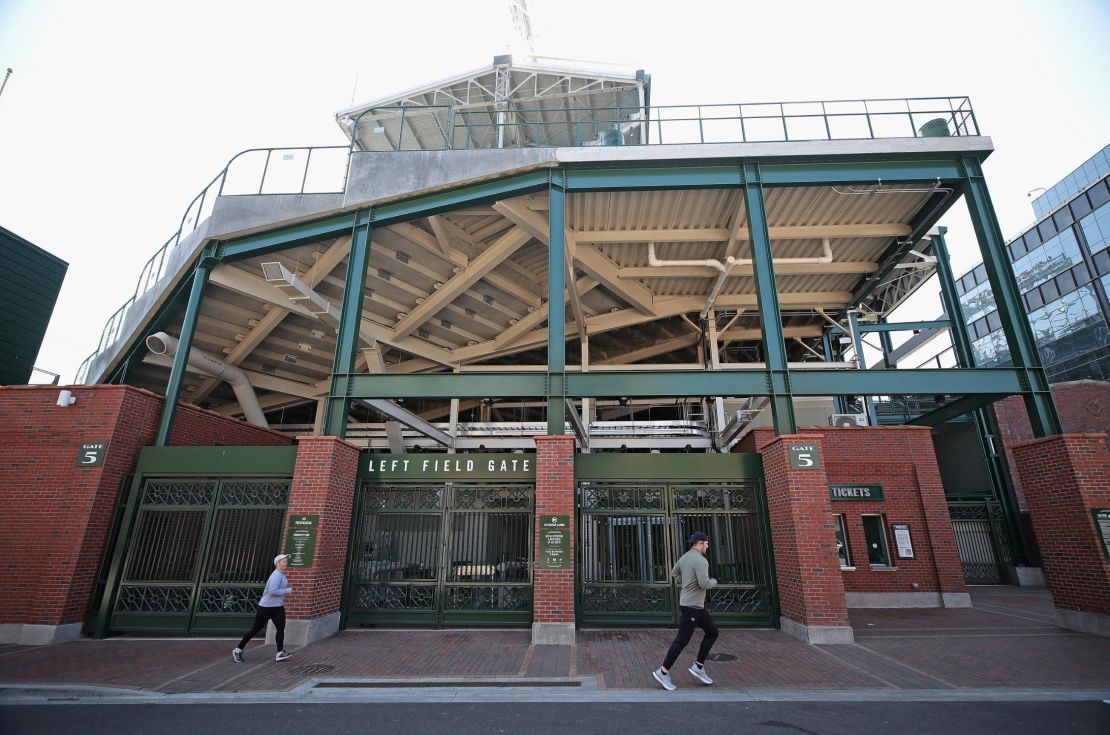 Joggers run past the entrance to Wrigley Field where the Chicago Cubs were scheduled to open its MLB season.