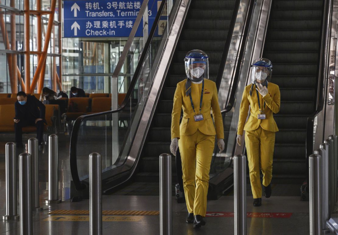 Staff wear protective masks and visors as they walk in the arrivals area at Beijing Capital International Airport on March 24.