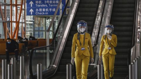 Staff wear protective masks and visors as they walk in the arrivals area at Beijing Capital International Airport on March 24.