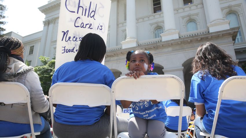 FILE - In this May 6, 2015, file photo Saryah Mitchell, sits with her mother, Teisa, Gay, left, a rally calling for increased child care subsidies at the Capitol in Sacramento, Calif. In much of the U.S., families spend more on child care for two kids than on housing. And if you're a woman, it's likely you earn less than your male colleagues even though one in four households with kids relies on mom as the sole or primary breadwinner. (AP Photo/Rich Pedroncelli, File)