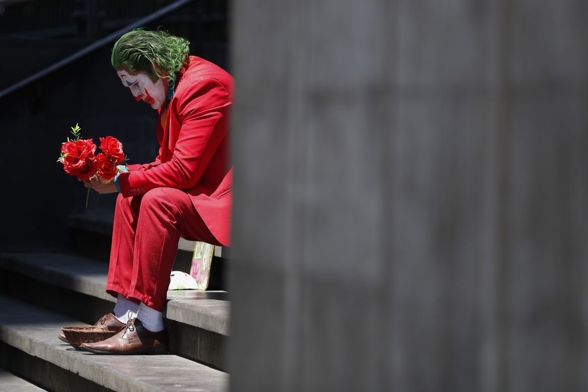 David Vazquez, a street performer dressed as the Joker, waits for pedestrians in Mexico City on Monday, March 23. He said business has plummeted for street performers, with few people stopping to take pictures because of the coronavirus.