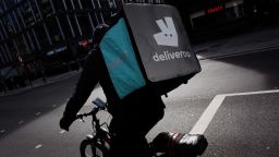 A Deliveroo courier cyclist waits at traffic lights on a near-deserted Tottenham Court Road in London, England, on March 21, 2020. Much of central London was virtually empty today, a day after British Prime Minister Boris Johnson ordered the closure of all pubs, bars, cafes and restaurants around the country. The move represents a toughening of measures to enforce the 'social distancing' that is being urged on citizens to reduce the growth of covid-19 coronavirus infections. Nightclubs, theatres, cinemas, gyms and leisure centres were also ordered closed. Some shops in the centre of capital remained open today, albeit mostly deserted of customers; many retailers however have temporarily closed their doors until the crisis abates. (Photo by David Cliff/NurPhoto via Getty Images)