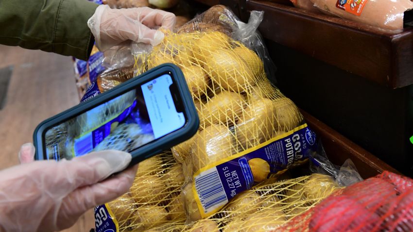 Instacart employee Monica Ortega uses her cellphone to scan barcodes showing proof of purchase for the customer while picking up groceries from a supermarket for delivery on March 19, 2020 in North Hollywood, California. (Photo by Frederic J. Brown/AFP/Getty Images)