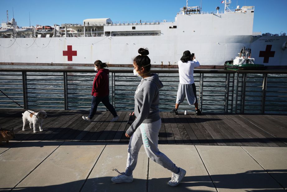 People wearing face masks walk near the USNS Mercy after the Navy hospital ship arrived in the Los Angeles area <a href="https://www.cnn.com/2020/03/27/us/california-hospital-ship-trnd/index.html" target="_blank">to assist local hospitals</a> dealing with the coronavirus pandemic.