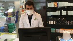 Ernesto Ruiz Lopez behind a protective screen at the counter of his Madrid pharmacy.