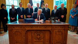 US President Donald Trump signs the CARES act, a $2 trillion rescue package to provide economic relief amid the coronavirus outbreak, at the Oval Office of the White House on March 27, 2020. - After clearing the Senate earlier this week, and as the United States became the new global epicenter of the pandemic with 92,000 confirmed cases of infection, Republicans and Democrats united to greenlight the nation's largest-ever economic relief plan. 