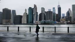 People walk in Brooklyn while lower Manhattan looms in the background on March 28, 2020 in New York City, NY. Across the country schools, businesses and places of work have either been shut down or are restricting hours of operation as health officials try to slow the spread of COVID-19. 