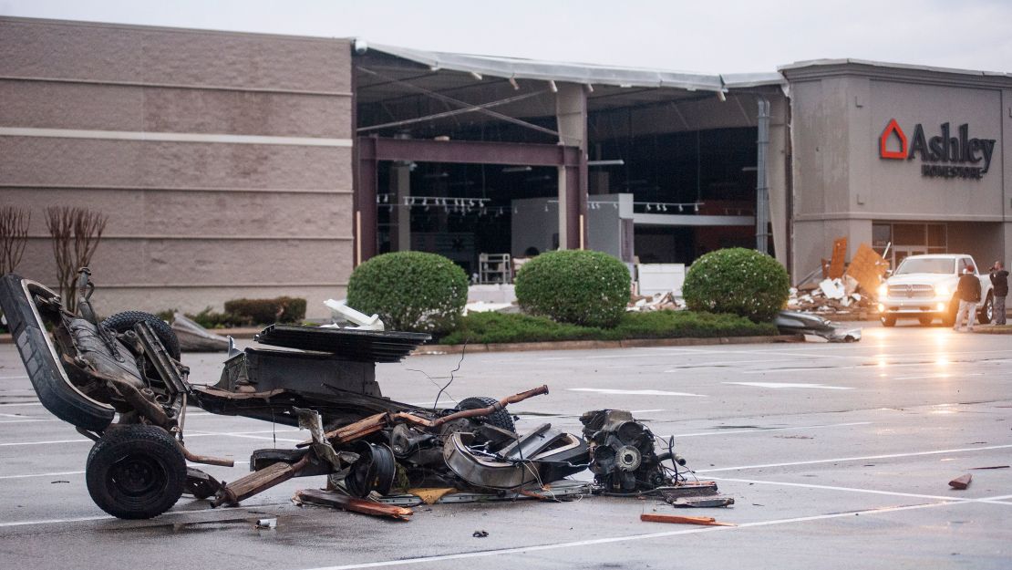The damaged remains of a vehicle lie in a parking lot outside a damaged Ashley HomeStore after the tornado Saturday in Jonesboro.