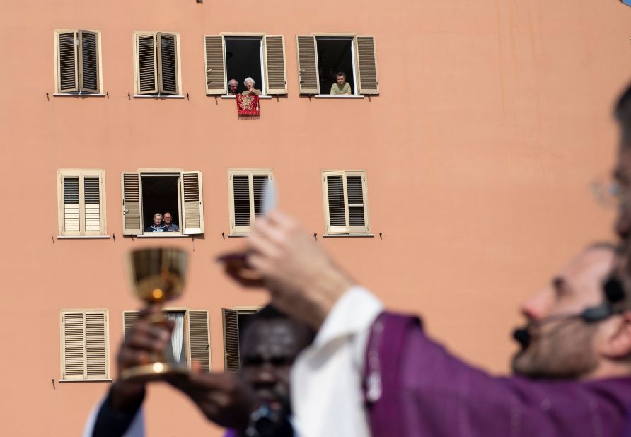 People listen from their homes as priests conduct Sunday mass from a church roof in Rome on March 29, 2020.