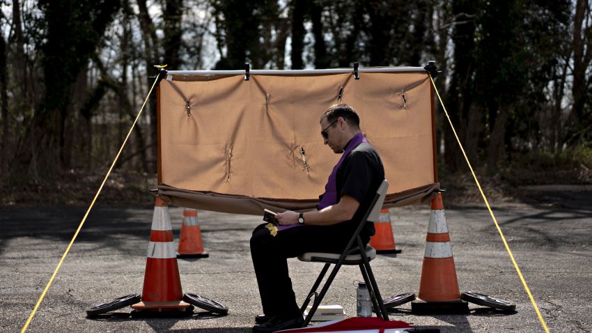 Father Matthew Fish reads while waiting for penitents at a drive thru confessional, set up in response to the coronavirus pandemic outside Holy Family Catholic Church in Hillcrest Heights, Maryland, U.S., on Friday, March 27, 2020. The U.S. is reeling from the effects of the global health crisis with infections topping 92,000, passing the number of cases in China where the disease first emerged. Photographer: Andrew Harrer/Bloomberg via Getty Images