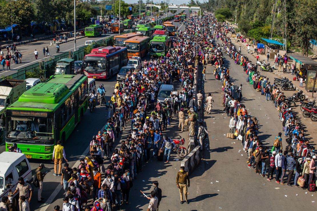 Indian migrant workers wait to board buses to return to their home villages as a nationwide lockdown continues on March 28, 2020, on the outskirts of New Delhi, India.