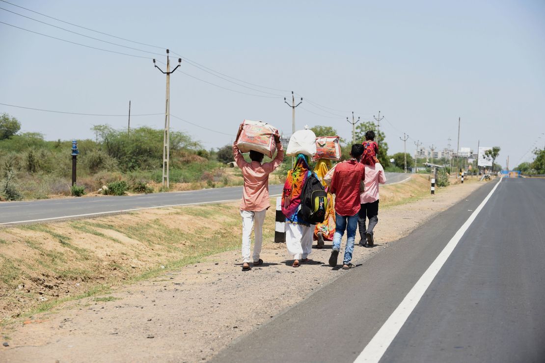 Migrant workers and their family members walk along a highway in a desperate bid to return to their village.