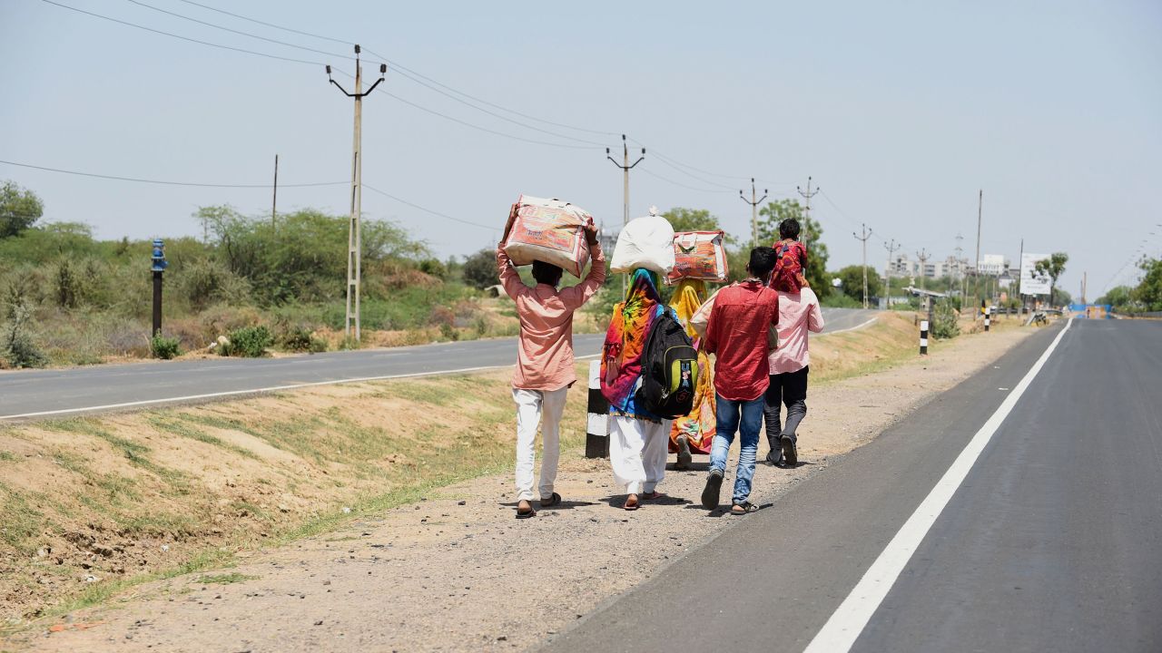 Migrant workers and their family members walk along a highway in a desperate bid to return to their village.